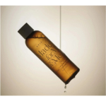 Un flacon marron de soin AXIS-Y « Made for Me » est suspendu dans les airs, incliné. Une goutte de liquide s'échappe de l'ouverture du flacon sur un fond neutre. Dakar