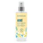 Un flacon pulvérisateur transparent de Brume Parfumée Hydratante Monoï BERDOUES avec une étiquette jaune, des accents bleus et des illustrations de fleurs tropicales promet « Hydrate - Sublime » et contient 95 % d'ingrédients naturels pour une expérience rafraîchissante. Dakar