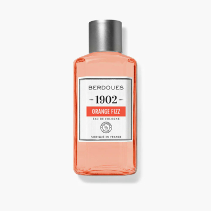 Une bouteille d'Eau de Cologne Berdoues 1902 Orange Fizz. Le flacon transparent contient un liquide orange et est muni d'un bouchon argenté. L'étiquette comporte le nom de la marque, le nom du produit et la mention « Fabriqué en France ». Dakar
