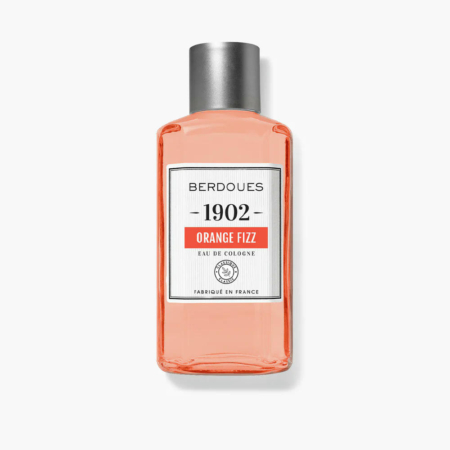 Une bouteille d'Eau de Cologne Berdoues 1902 Orange Fizz. Le flacon transparent contient un liquide orange et est muni d'un bouchon argenté. L'étiquette comporte le nom de la marque, le nom du produit et la mention « Fabriqué en France ». Dakar