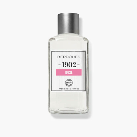 Flacon en verre transparent du parfum Berdoues 1902 Rose, doté d'un bouchon argenté et d'une étiquette aux inscriptions noires et roses. L'étiquette indique « Berdoues 1902 Rose, Fabriqué en France ». Dakar