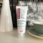 Un tube de soin anti-imperfections Boréade CL est posé sur une étagère, avec en arrière-plan flou des livres, un vase blanc et une tasse bleu sarcelle avec sa soucoupe. Le produit revendique des propriétés non comédogènes et anti-imperfections. Dakar