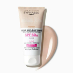 Un tube de crème teintée anti-âge Byphasse SPF 50+ se détache sur un fond blanc. La crème beige tourbillonne à côté du tube, révélant sa texture. L'étiquette met en avant la protection UVA et les propriétés hydratantes. Dakar