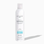 Bouteille cylindrique blanche d'Eau Thermale Byphasse, étiquetée « eau thermale 100 % naturelle ». Son design bleu clair et gris, d'une contenance de 300 ml (10,14 fl oz), projette une ombre sur une surface claire. Dakar