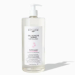 Flacon transparent de gel douche Dermo Micellaire Byphasse avec pompe blanche. L'étiquette présente les informations produit et un design rose clair. Le volume est de 1 litre (33,8 oz liq.). Le fond est blanc uni. Dakar