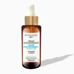 Flacon marron de Sérum Ultra-Hydratant Byphasse avec bouchon compte-gouttes blanc sur fond blanc. L'étiquette porte l'inscription « Acide Hyaluronique » en bleu, soulignant ses propriétés hydratantes et lissantes grâce à la provitamine B5. Dakar