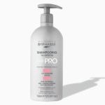Flacon blanc de shampoing Byphasse Liss Extrême Hair Pro avec pompe doseuse. D'une contenance de 750 ml (25,36 fl oz), il est imprimé en français et en anglais. Il projette une ombre légère sur un fond uni. Dakar