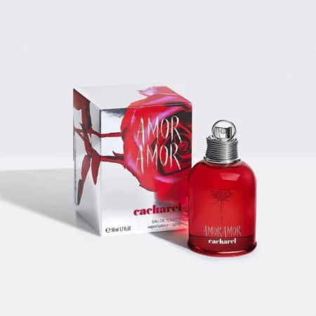 Un flacon de parfum CACHAREL AMOR AMOR 50 ml est posé à côté de son écrin. Le flacon rouge sophistiqué, orné d'une rose, s'accorde parfaitement avec l'écrin, orné d'un motif audacieux de rose rouge et du nom du parfum en lettres blanches éclatantes. Dakar