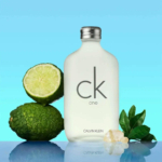 Un flacon de parfum CK One est présenté sur un fond bleu dégradé. Il est entouré de citrons verts frais, de feuilles vertes et de petits cristaux blancs, reflétant une ambiance fraîche et naturelle. Dakar