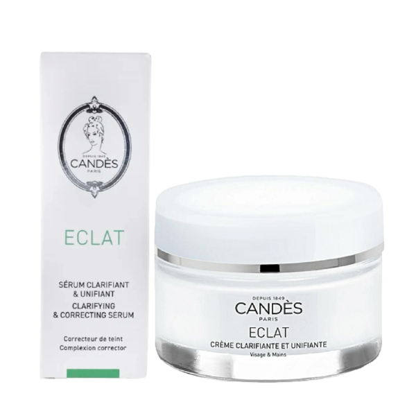 Un pot blanc de crème visage et mains Candès Éclat se trouve à côté de sa boîte blanche assortie. La boîte porte l'inscription « Sérum Clarifiant et Correcteur » et arbore le logo Candès Paris sur le dessus. Dakar