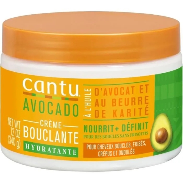 Un pot de crème hydratante bouclante à l'avocat Cantu. L'étiquette met en avant l'avocat et le beurre de karité, et précise que ce produit est conçu pour nourrir et définir les cheveux bouclés, frisés, crépus et ondulés. Le pot contient 340 g (12 oz). Dakar