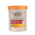 Un pot de 524 g de gel coiffant fortifiant au beurre de karité Cantu à l'huile de ricin noire de Jamaïque. L'emballage est transparent avec un couvercle orange et les informations produit sont en vert et rouge. Dakar