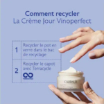 Gros plan d'une personne tenant un pot ouvert de crème Caudalie sur fond bleu. Le texte sur l'image fournit des instructions de recyclage en français pour le pot en verre et le bouchon du produit. Dakar