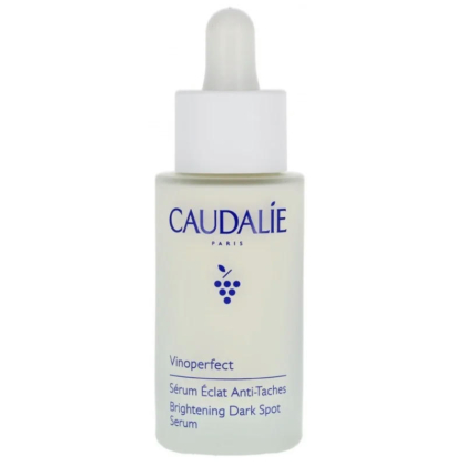 Un flacon de Sérum Éclat Anti-Taches Vinoperfect de Caudalie avec un bouchon compte-gouttes. Le flacon est blanc cassé avec un texte bleu et une petite illustration de raisin. Dakar
