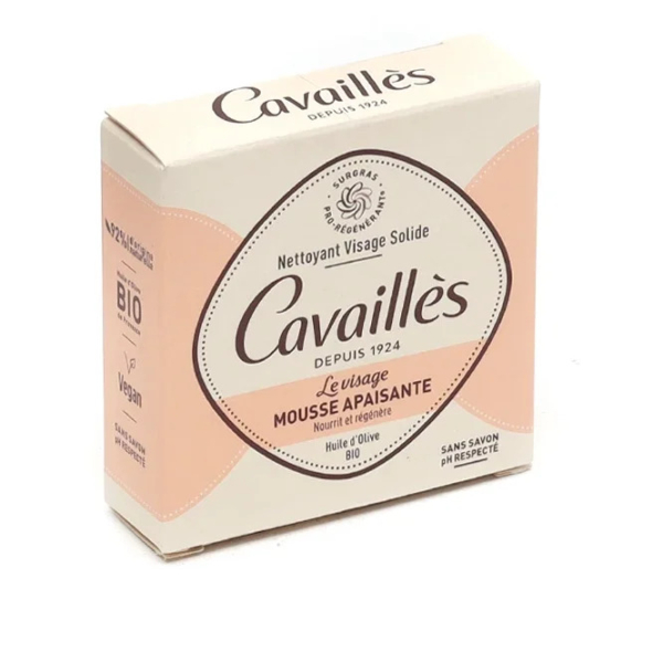 L'image montre une boîte beige et pêche du nettoyant visage solide Cavaillès. L'emballage met en avant des caractéristiques telles que le véganisme, le bio, l'absence de savon et les vertus apaisantes de l'huile d'olive. Dakar