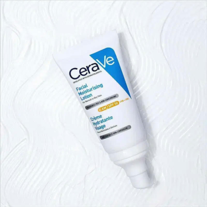 Un tube de Lotion Hydratante Visage CeraVe avec SPF 50 est posé sur une surface blanche texturée. L'emballage, blanc avec des inscriptions bleues et noires, est équipé d'une pompe doseuse. Dakar