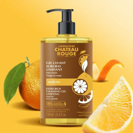 Un flacon de Gel Nettoyant Extra Riche Château Rouge est présenté sur un fond d'oranges et de tranches de citron. L'étiquette du produit précise qu'il est destiné au visage et au corps et qu'il contient des agrumes, soulignant ainsi ses vertus nourrissantes. Dakar