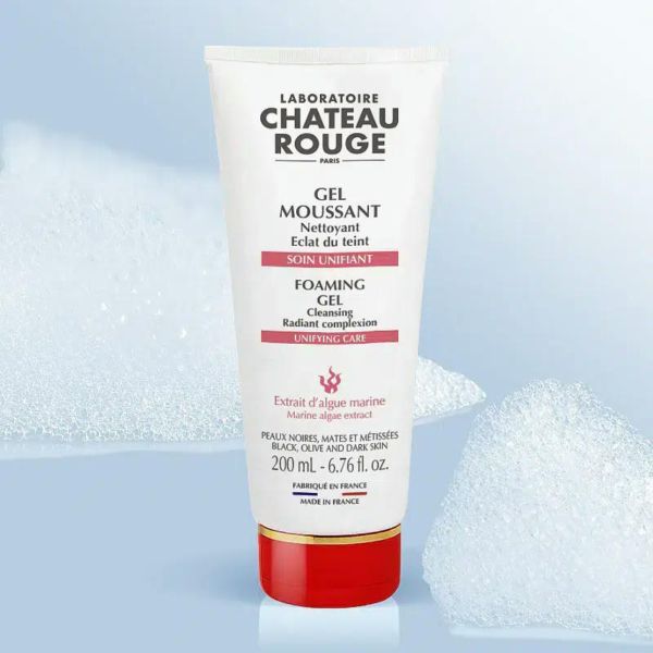 Un tube de Gel Nettoyant Moussant Laboratoire Château Rouge est centré sur un fond bleu clair orné de bulles de mousse. Blanc, il est rehaussé de touches de rouge et porte l'inscription « Teint Éclat ». Son poids net est de 200 ml. Dakar