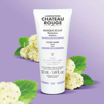 Un tube de Masque Éclat Château Rouge Paris se détache sur un fond violet dégradé. Des mûres blanches et des feuilles vertes sont dispersées. Le texte sur le tube met en valeur des caractéristiques telles que « Éclat », « Anti-taches » et « Extrait de mûrier blanc bio ». Dakar