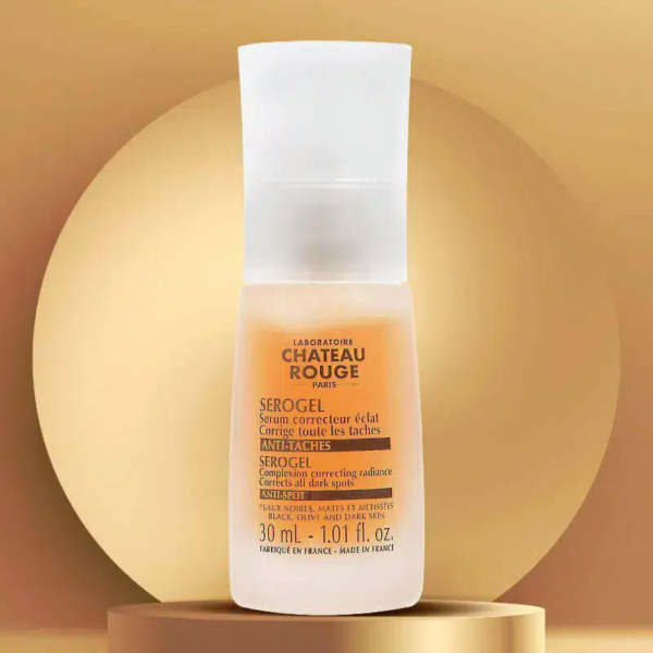 Un flacon de SeroGel Château Rouge trône sur un socle doré. Ce gel correcteur d'éclat de 30 ml arbore une étiquette aux couleurs orange et blanc sur un fond doré dégradé. Dakar