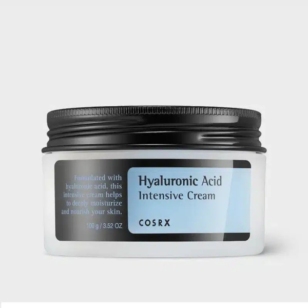 Un pot blanc avec un couvercle noir, étiqueté « Crème Intensive à l'Acide Hyaluronique » de COSRX. L'étiquette indique qu'elle aide à hydrater et nourrir la peau en profondeur. Le pot contient 100 g. Dakar