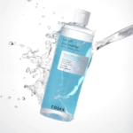 Un flacon d'Eau Micellaire Nettoyante Niacinamide à Faible pH COSRX est entouré d'éclaboussures d'eau. Le flacon transparent contient un liquide bleu et est étiqueté pour les peaux sensibles, avec des propriétés hydratantes. Dakar