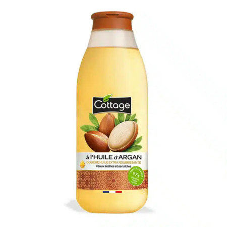 Un flacon d'huile de douche Cottage à l'huile d'argan. L'étiquette présente des noix et des feuilles d'argan. Ce produit est destiné aux peaux sèches et sensibles, avec 97 % d'ingrédients naturels. Son bouchon marron est orné du drapeau français. Dakar