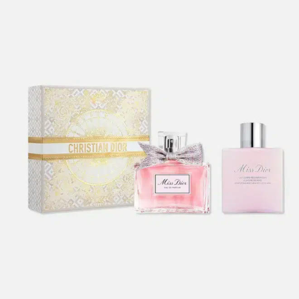 Coffret cadeau Miss Dior composé d'un flacon de parfum rose orné d'un nœud argenté et d'un flacon de lotion assorti. Le coffret décoratif blanc et or arbore le nom de la marque Christian Dior. L'ensemble est présenté sur un fond blanc uni. Dakar