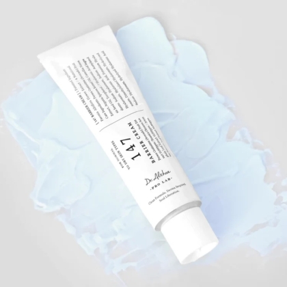 Un tube blanc étiqueté « Dr Althea 147 Crème Barrière au Resvératrol et à l'Adénosine 50 ml » est posé en diagonale sur un fond texturé bleu clair, avec un texte et une marque élégants mis en valeur par son bouchon blanc immaculé. Dakar