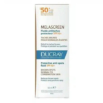 La boîte du Fluide Protecteur Anti-Taches SPF 50+ Ducray Melascreen est étiquetée en français et en anglais. Conçu pour les peaux normales à mixtes, il atténue les taches brunes. La boîte est principalement blanche avec des inscriptions bleues et marron. Dakar
