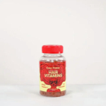 Une bouteille en plastique transparent avec un bouchon rouge contenant des vitamines capillaires. L'étiquette rouge et jaune présente une illustration de cheveux longs et les inscriptions « Halo Beauty » et « Vitamines capillaires » sur le devant. Le flacon est sur fond blanc uni. Dakar