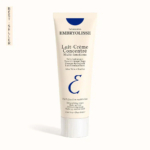 Un tube de Lait-Crème Concentré Embryolisse est présenté sur fond blanc. L'emballage est orné d'un texte bleu et noir, soulignant sa nature hydratante multifonctionnelle à l'aloe vera et au beurre de karité. Une étiquette « Meilleure vente » figure sur le côté. Dakar