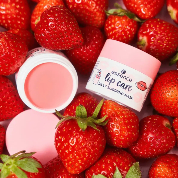 Un masque de nuit en gelée pour les lèvres, présenté dans un contenant rose, est entouré de fraises fraîches. Le pot ouvert, révélant le produit rose qu'il contient, se trouve à côté du pot fermé. La présentation met en valeur le thème de la fraise. Dakar