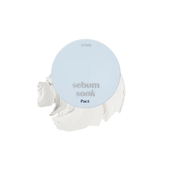 Un compact bleu clair portant le texte « sebum soak Pact » sur le dessus, avec une substance crémeuse beige visible derrière, probablement de la poudre pour le visage ou du maquillage à la texture lisse. Dakar