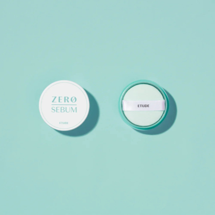 Vue de dessus du poudrier Zero Sebum d'Etude, ouvert pour révéler une houppette blanche. Le poudrier et son couvercle, ronds et turquoise clair, reposent sur un fond turquoise assorti. Dakar