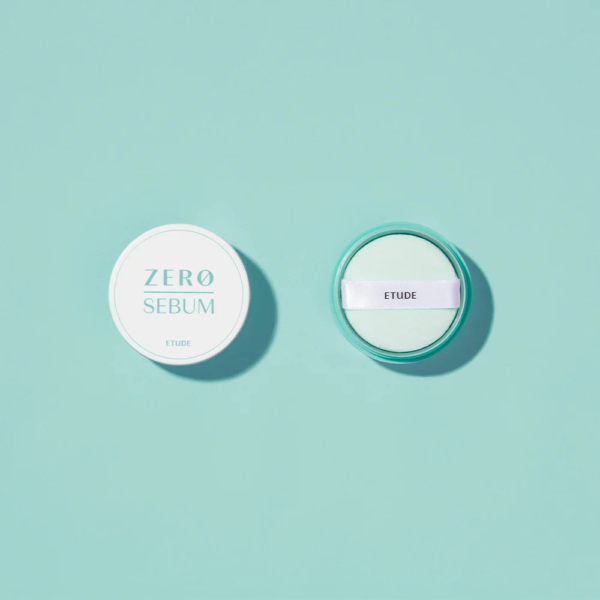 Vue de dessus du poudrier Zero Sebum d'Etude, ouvert pour révéler une houppette blanche. Le poudrier et son couvercle, ronds et turquoise clair, reposent sur un fond turquoise assorti. Dakar