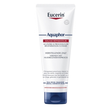 Un tube d'Eucerin Aquaphor Baume Réparateur Cutané 198 g présente un corps blanc et un bouchon bleu avec une étiquette frontale en français et en néerlandais, soulignant son pouvoir de régénération et de réparation des peaux sèches et craquelées. Dakar
