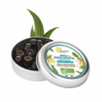 Une boîte ronde argentée étiquetée « Gommes Bio Propolis-Eucalyptus » dont le couvercle ouvert révèle des bonbons ronds et foncés. Des feuilles vertes sont disposées à l'arrière, soulignant le côté naturel du produit. Dakar