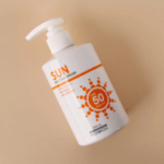 Flacon pompe blanc de crème solaire SPF 50+ PA+++, portant l'inscription « Sun Multi Sun Cream » sur fond beige. Le flacon est orné d'un texte orange et d'un motif soleil. Contient 250 ml, par Foodholic. Dakar