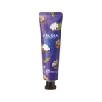 Tube de crème pour les mains au beurre de karité Frudia My Orchard sur fond blanc. Le tube est violet foncé avec des motifs de noix de karité et de feuilles vertes. Le nom de la marque « Frudia » est bien visible. Dakar