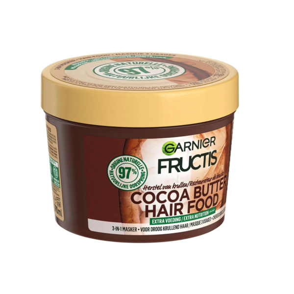 Un pot rond de soin capillaire Garnier Fructis au beurre de cacao avec un couvercle beige. L'étiquette indique qu'il s'agit d'un masque 3-en-1 pour cheveux secs, composé à 97 % d'ingrédients d'origine naturelle. Le design est orné d'images de fèves de cacao. Dakar