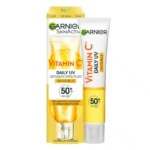 Un tube de Garnier SkinActive Vitamine C Fluide UV Quotidien Ultra-Léger avec SPF 50+ est posé à côté de sa boîte jaune et blanche. L'emballage porte les mentions « invisible » et « LSF – Jeden Tag », qui indiquent une protection solaire quotidienne. Dakar