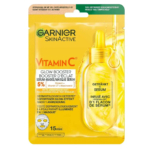 L'image montre un paquet de Garnier SkinActive Glow Booster Serum-Mask avec vitamine C. L'emballage est jaune avec un texte mettant en évidence 5 % de vitamine C + niacinamide et prétend montrer des résultats en 15 minutes. Dakar