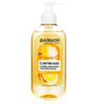 Un flacon pompe transparent portant l'inscription « Garnier Skin Naturals Vitamin C Clarifying Wash ». Le produit est censé purifier, illuminer et sublimer l'éclat. Une orange tranchée est visible à l'intérieur. Conçu pour les peaux ternes. Testé dermatologiquement. Dakar