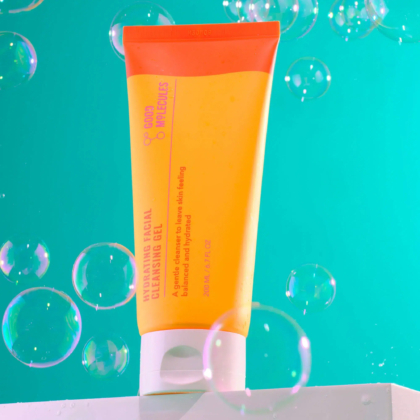 Un tube orange et jaune vif de Gel Nettoyant Hydratant Visage Good Molecules est posé sur une surface blanche. Des bulles de différentes tailles flottent autour, sur fond vert. Le texte sur le tube est partiellement visible. Dakar