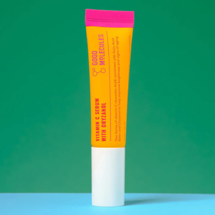Un tube jaune vif de sérum à la vitamine C Good Molecules avec Orizanol se dresse sur un fond vert et bleu. Le bouchon est magenta et le nom du produit est imprimé verticalement en rouge. Dakar