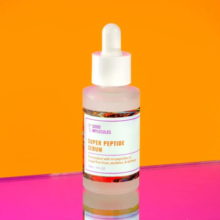 Un flacon de sérum Super Peptide avec un bouchon compte-gouttes, sur fond orange vif. Le flacon est orné d'une étiquette blanche avec texte, dont le reflet est visible sur une surface rose en dessous. Dakar