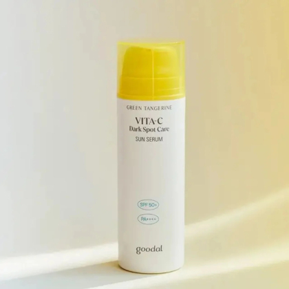 L'image montre un flacon de sérum solaire Goodal's Green Tangerine Vita-C Dark Spot Care. Le flacon est blanc avec un bouchon jaune, offrant une protection SPF 50+ et PA++++. Il est posé debout sur un fond doux et neutre. Dakar