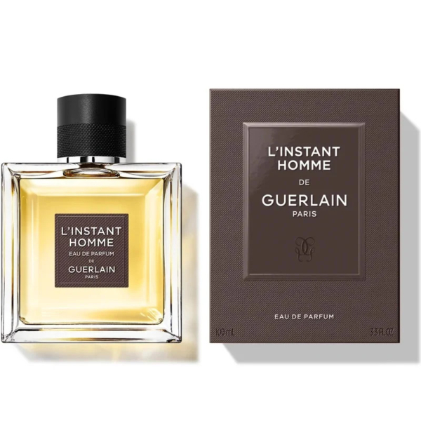 Un flacon d'eau de parfum L'Instant Homme de Guerlain est présenté à côté de son coffret. Le flacon, carré, est coiffé d'un bouchon noir et contient un liquide doré. Le coffret est noir avec un texte blanc et doré. Tous deux présentent un design simple et élégant. Dakar