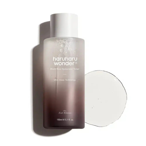 Un flacon de tonique hyaluronique Haruharu Wonder au riz noir, avec un bouchon blanc, posé sur une surface blanche. Le flacon semi-transparent laisse apparaître le liquide à l'intérieur, à côté d'un liquide translucide. Le texte sur le flacon décrit les caractéristiques du produit. Dakar